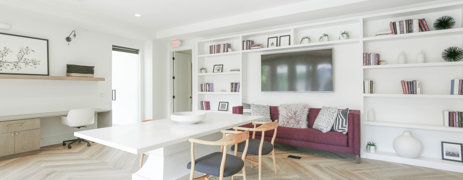 Work from home lounge with table, tv, and built in shelves filled with decor